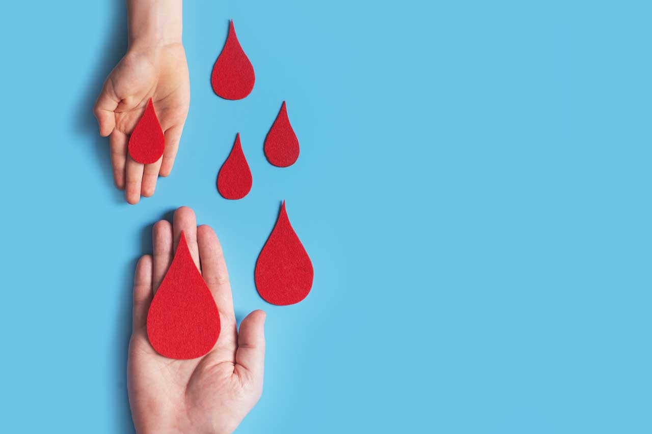 Deux mains tenant des gouttes rouges symbolisant le don de sang