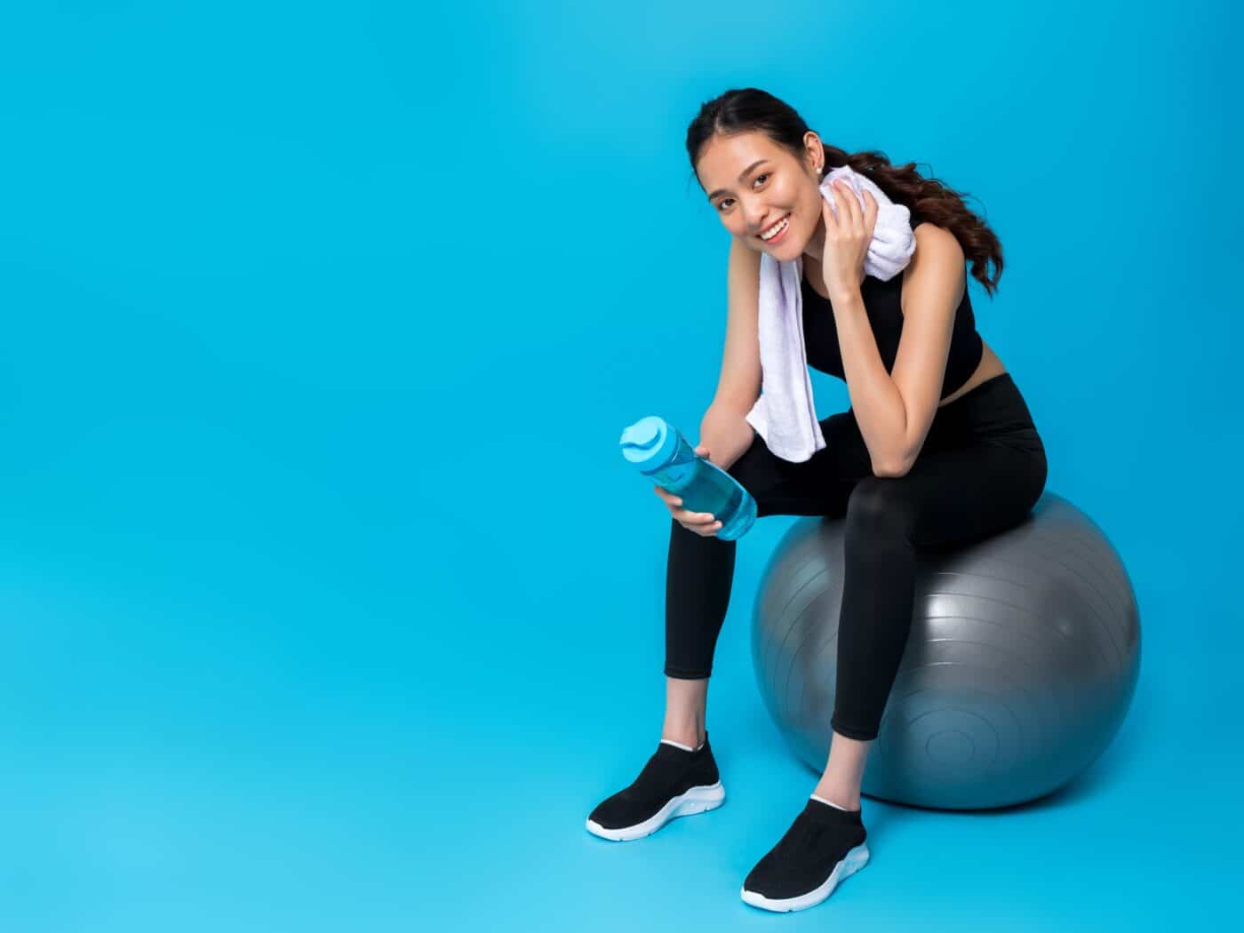Femme en tenue de sport assise sur un ballon d'exercice