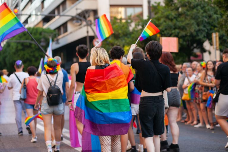 personnes qui manifestent avec des drapeaux arc-en-ciel