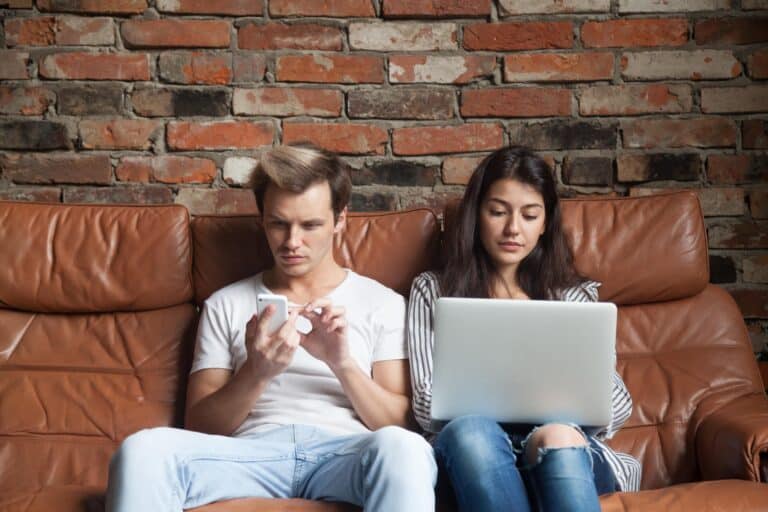 2 personnes qui sont un téléphone et un ordinateur