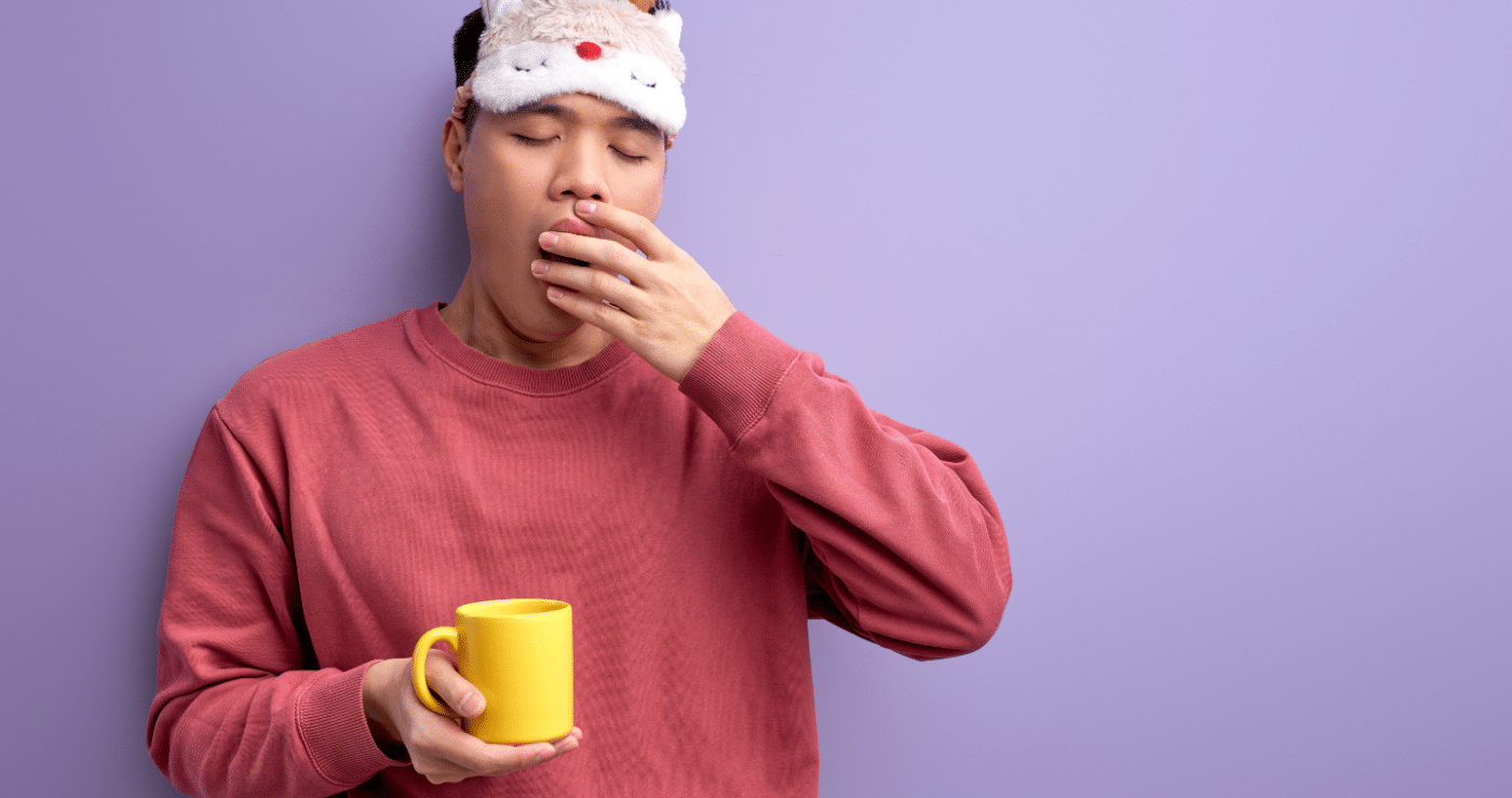 Homme avec un masque de sommeil et une tasse dans la main